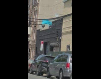 Guy on standing on rooftop spray painting another building