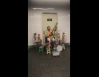 Man sing and plays guitar with dancing dolls around him