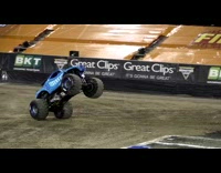 Blue monster truck drives up ramp in race track and flips over upside down