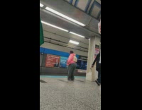 Guy wearing pink sweater dances while waiting for subway