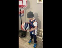 Boy wearing jersey dribbles and dunks on small hoop