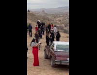 Woman red dress poses beside car at canyon