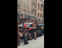 Collab WINY - Woman poses for picture in front of fire truck near burning building
