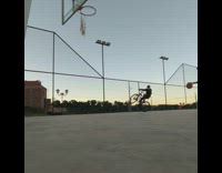 One guy rides bicycle other plays basketball