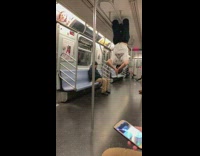 Guy hangs upside down from ceiling handrails on subway
