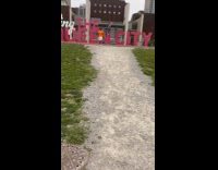 Collab IITW - Woman sits and poses on the letter N of the Queen City signage