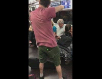 Man plays the violin on subway while woman sitting in front of him plugs her ears