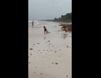 Woman in bikini bend and kneels at the beach