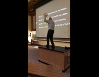 College professor dancing on table in class with tambourine