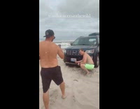 Guy green shorts sit black SUV beach