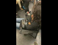 Woman sits on black lawn chair at subway