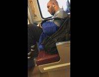 Man earphones blue backpack puts feet up on chair and takes up extra seat on train