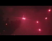 Crowd watches red fireworks celebration water night