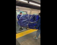 Two guys carry large object tarp subway