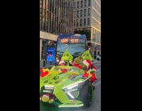 Person in Grinch costume rides grinch autocycle