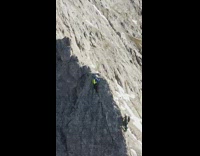 Two people climb on ledge of mountain