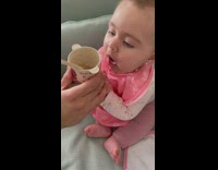 Baby gives excited reaction to being handed cup of smash bananas