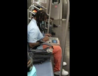 DJ plays music with board on lap on subway 