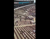 People hold up long stick together bleachers