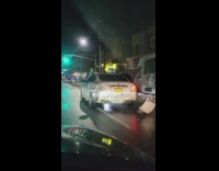 White car driving on road with rear bumper barely hanging on 
