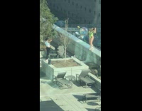 Girl holding balloons stands rooftop railing wall