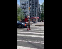 Man covered in rainbow paint skates on street 
