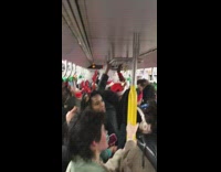 Subway passengers in Christmas gear sing Rudolph the Red nose reindeer on train together