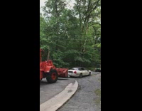 Red bulldozer tows white convertible car chain 
