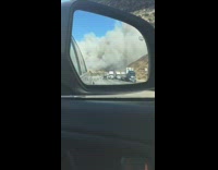 Large wildfire viewed from the sidemirror of car