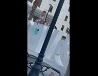 Woman kneels on the signage while man fixes her shorts