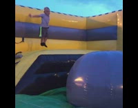 Boy bounces off blue ball in bounce house