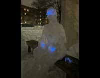 Snow sculpture person on bench blue lights 