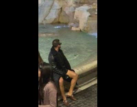 Man in black leather coat sits by the water fountain