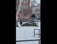 Guy tries to skateboard with no wheels off of park table in the snow 
