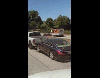 White pickup truck towing a mercedes sedan on the freeway 
