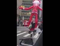 Woman dancing with a giant blow up santa doll on her back