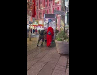 Two people push metal food cart down sidewalk