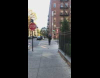 Man Crosses Street as he Holds Speaker