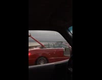 Surfboard sticks out of red convertible car