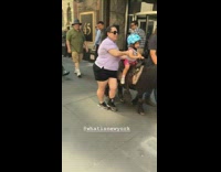 little girl blue helmet riding black mini small horse through sidewalk street