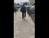 Guy struggles to ride unicycle down sidewalk 
