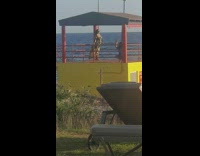 Girl poses yellow red gazebo ocean water 