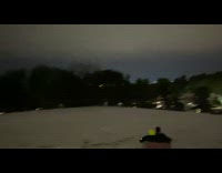 Two people sled down hill inside canoe