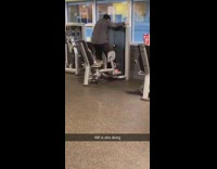 Woman stands up while exercising on thigh opening machine at the gym