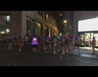 Group of people in glow in the dark outfits cross street 