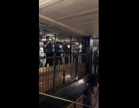 People crossing flood climbing onto subway gate railings