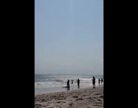 Man on a mermaid costume on the beach curled up