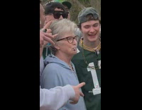 Old woman poses with college kids 