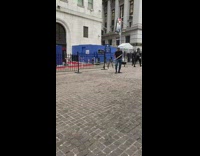 Man with instrument and bells tip toes on sidewalk and makes bell noise