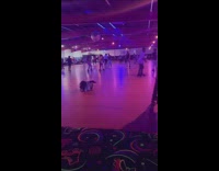Guy on roller skates falls into skating rink with blue purple lights